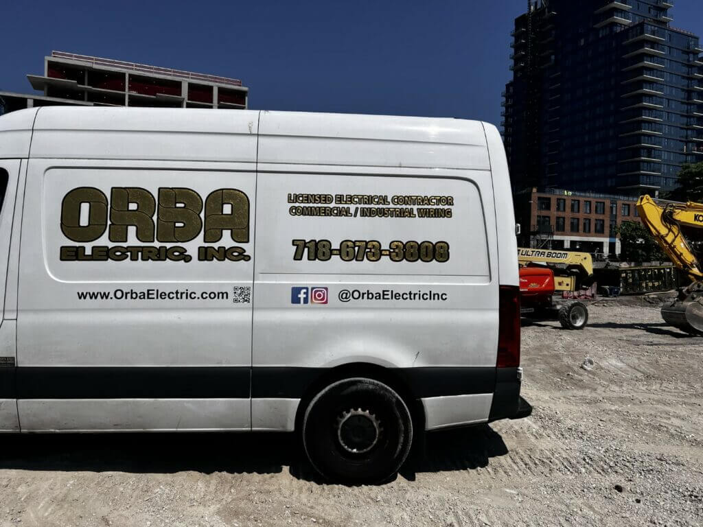 White van with company logo and contact info, parked at construction site