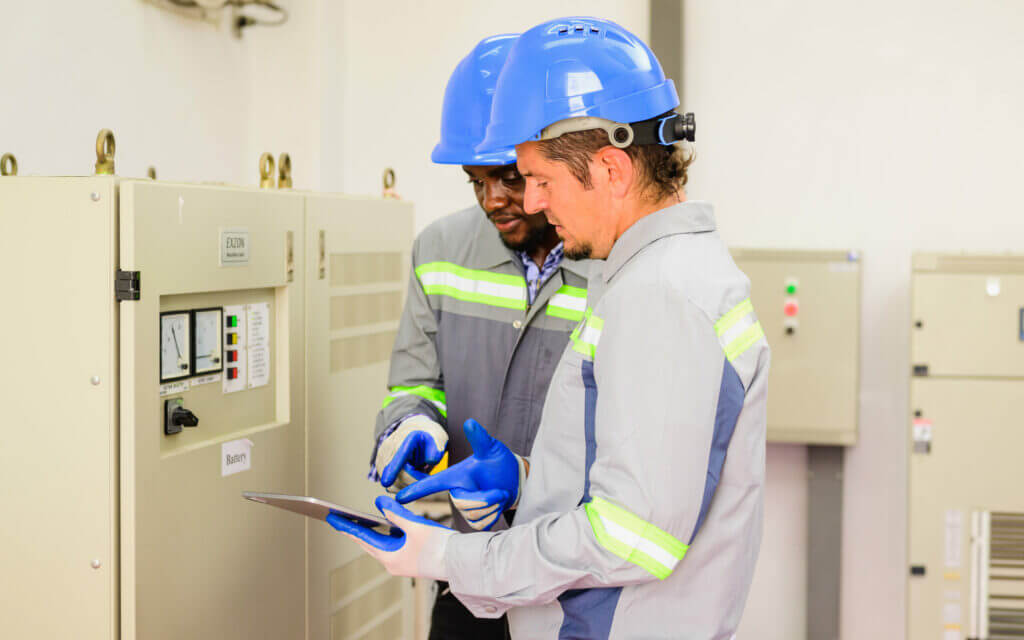 Engineers inspecting electrical equipment on a digital tablet
